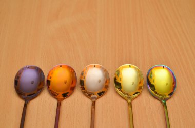 Sade ahşap bir zemin üzerinde çok renkli masa kaşıkları, masa takımı veya çatal bıçak hakkında bir makale için fotoğraf, kopyalanmış bir alan