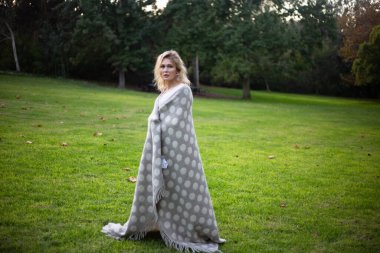 Parkta dans eden bir kadını sıcak ekose ya da battaniyeli benekle güzelleştir.