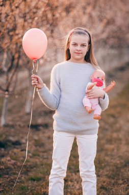 Kız elinde bir oyuncak bebek tutuyor. O bir maske takıyor. Bahar geldi..