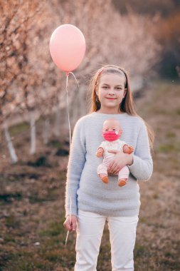 Kız elinde bir oyuncak bebek tutuyor. O bir maske takıyor. Mutlu yıllar.!