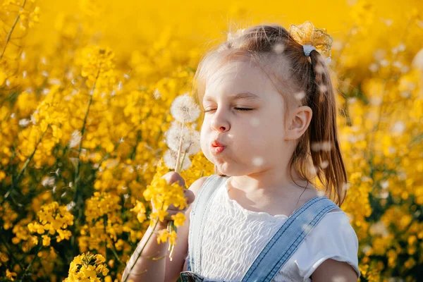 Dívka Žlutých Květinách Fouká Pampelišku — Stock fotografie
