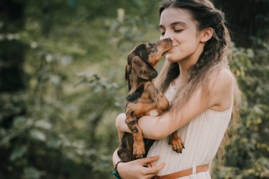 Kız dachshund köpeğiyle ormanda yürüyor..