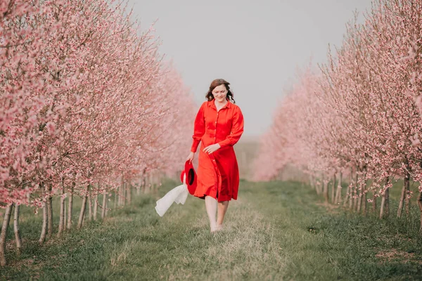Zahradou Prochází Žena Červených Šatech Červeném Klobouku Procházka Přírodě Jarní — Stock fotografie