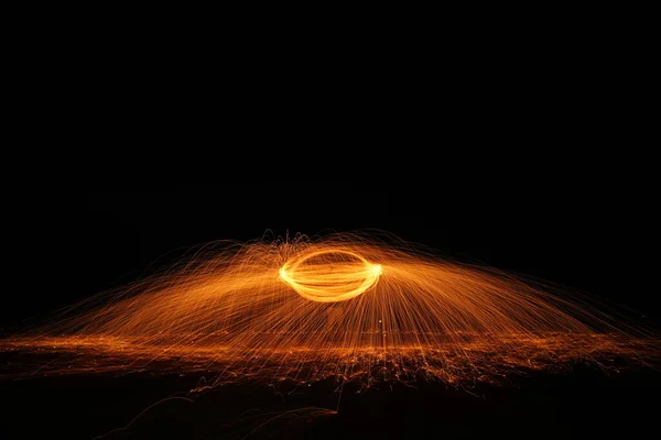 回転と燃焼長速度シャッターで円形状のスチールウールの輝き火災は地面に輝く光ラインを撮影します — ストック写真