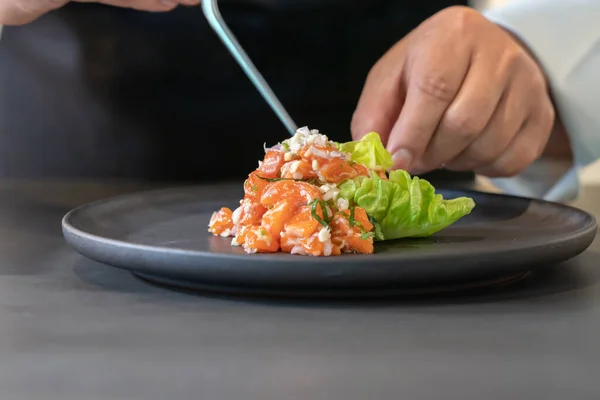 主厨手中的除草机厨师在食物上用微药草装饰调味的鲑鱼沙拉 — 图库照片