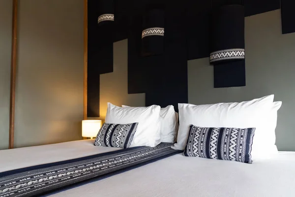 Modern White bed and dark blue pillow combination of vintage wooden bedroom Asian style.