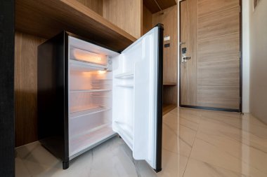 Ahşap tezgahın altında küçük bir buzdolabı açtı ve otel ve tatil yerindeki delux odasına girdi..