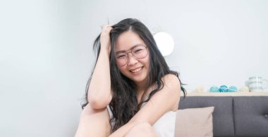 Asyalı Gözlüklü Kadın sabah yatak odasında yatağında dinleniyor..