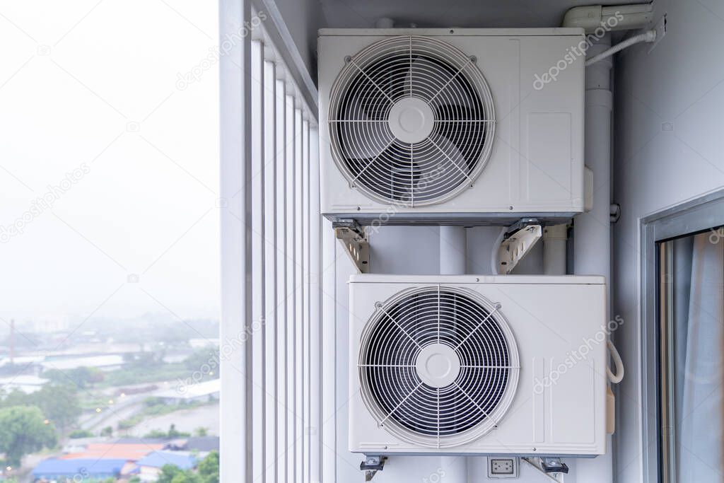 two air conditioning compressors are hung on wall.