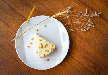 Ahşap masadaki beyaz tabakta hindistancevizi kremalı turta var. Güneş ışığında çekim yapmak..