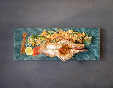 Flatlay Toptable to the Lobster Pad Thai stüdyo ışığı altında kızarmış şehriye, tofu ve diğer malzemelerle servis yapmaya hazır. Kesme Yolu.