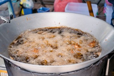 Asya usulü kızarmış tavuk büyük tavada palmiye yağı ile kızartılır..