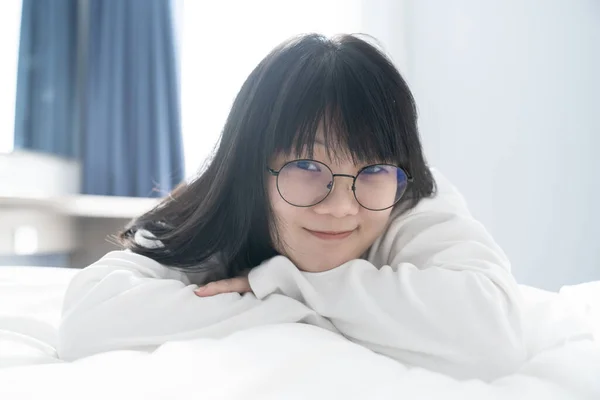 Uma Menina Asiática Doce Fofa Seus Óculos Pretos Deita Cama — Fotografia de Stock
