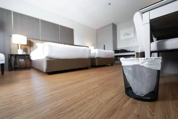 A container trash in the room with plastic inside it in hotel and resort bedroom with wooden floor and furniture background.