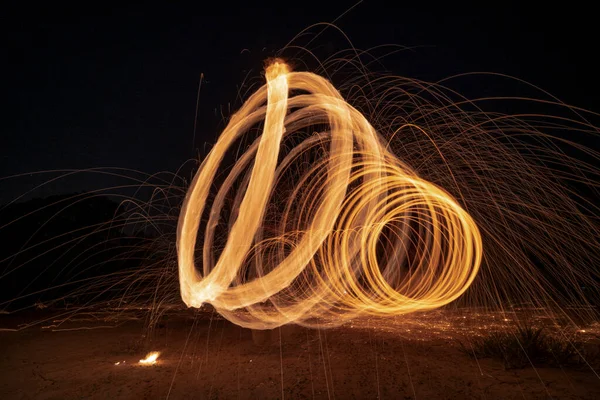 回転と燃焼長速度シャッターで円形状のスチールウールの輝き火災は地面に輝く光ラインを撮影します — ストック写真