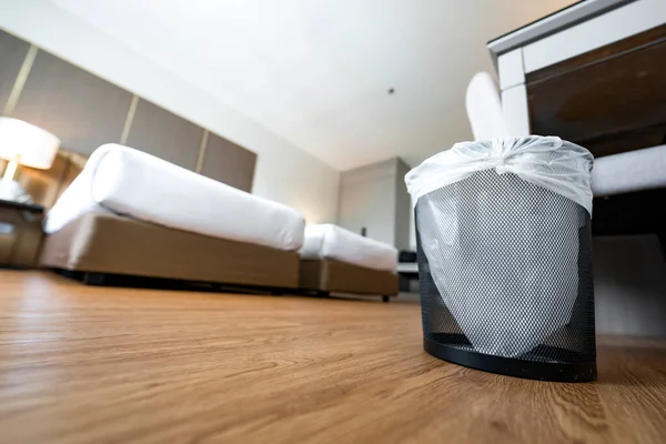 A container trash in the room with plastic inside it in hotel and resort bedroom with wooden floor and furniture background.