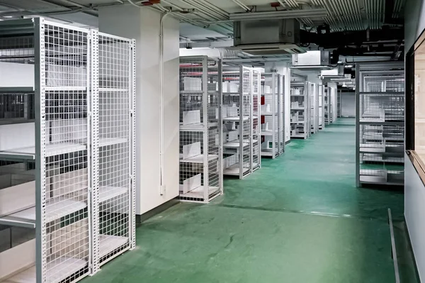 White shelves are lined up all over the area in a warehouse with a green floor. It also has an excellent security system.