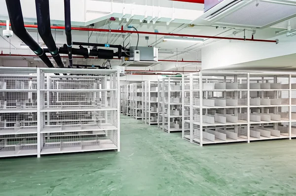 White shelves are lined up all over the area in a warehouse with a green floor. It also has an excellent security system.