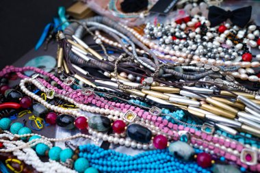 Raflarda çeşitli renk, şekil ve malzemelerden yapılmış kolyeler var. Bileşimi farklı olmasına rağmen, daha olumlu bir görünüm yaratıyor..