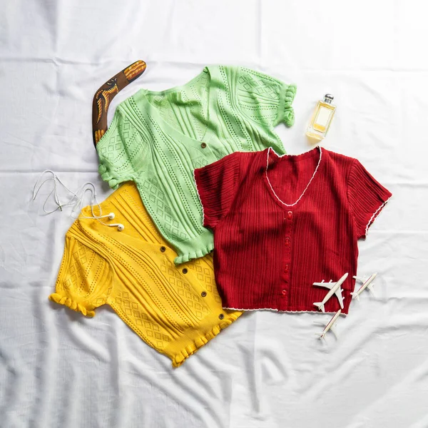 The five crop tops are yellow, light green, crimson, were placed against on a white backdrop for a clothing advertisement on social media.