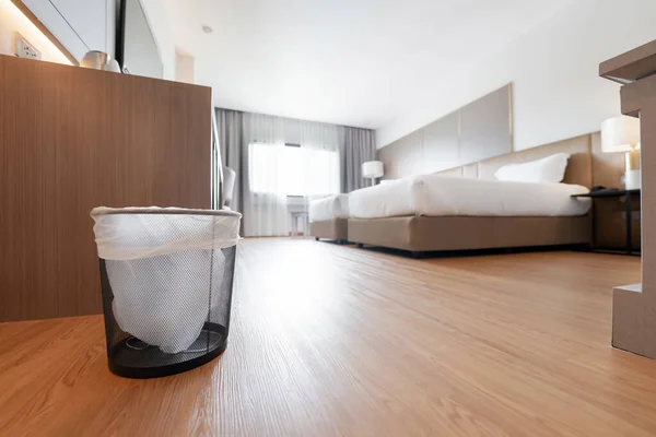 A container trash in the room with plastic inside it in hotel and resort bedroom with wooden floor and furniture background.