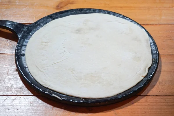 After kneading the pizza dough, it is placed in a pizza baking pan to expand to the proper size and is ready for the next step.