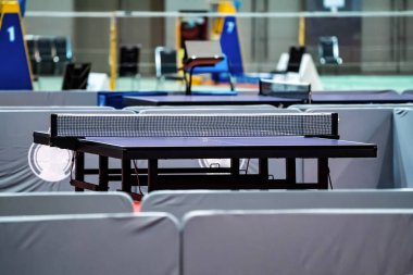 Blue table tennis or pingpong table is settle on a red, orange floor of the indoor court stadium for competitions tournament.