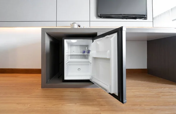 Black mini small fridge refrigerator under the frame wooden counter in hotel resort bedroom