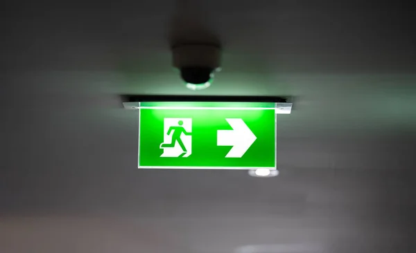 fire exit sign light box is hung on the ceiling in hotel walk way.