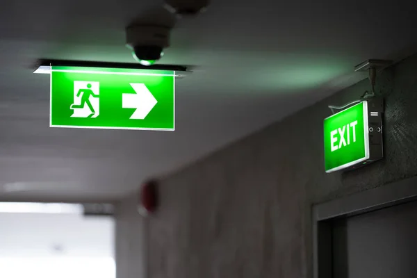 Green Fire Exit Sign Placed Ceiling Dimly Lit Corridor Green Stockbild