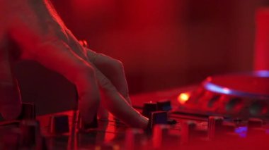 DJ hand and finger are closed up between he controls the Mixer Sound Console board Machine.