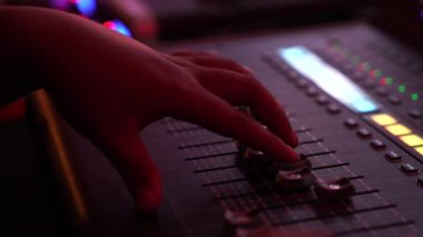 DJ hand and finger are closed up between he controls the Mixer Sound Console board Machine.