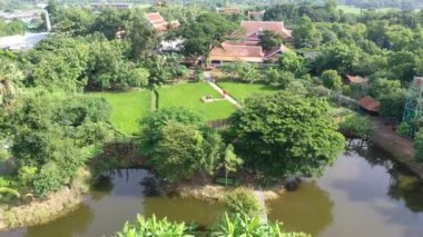 Drone view of Sufficiency Economy, Land full of agricultural activities with green rice fields, big ponds, and trees. Small houses and temple close by a pond.