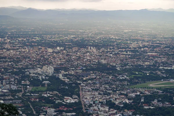 Top view of mountain in Chiang Mai City, Thailand. White cloud and dust is above of the mountain while cities can be seen far away.