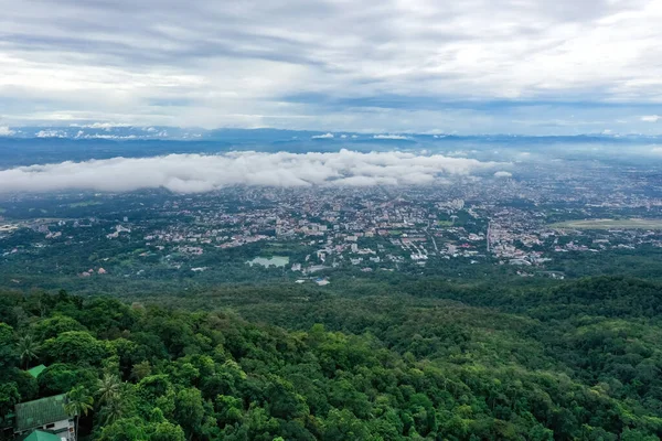 Top view of mountain in Chiang Mai City, Thailand. White cloud and dust is above of the mountain while cities can be seen far away.