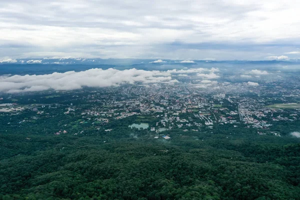Top view of mountain in Chiang Mai City, Thailand. White cloud and dust is above of the mountain while cities can be seen far away.