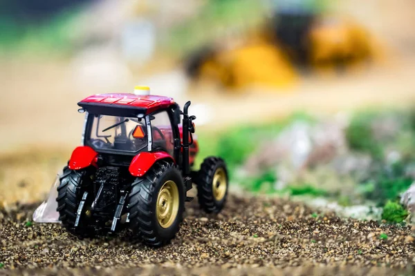 Orange toy tractor laying on the ground in the garden where the background was blurred.