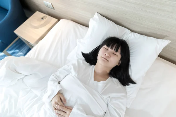 Asian woman sleeps on white bed after exhausted and tried all day.