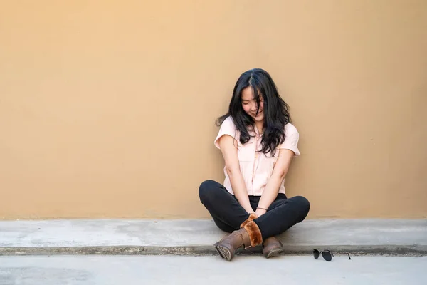 The Asian woman is sitting, crying and smiling alone at the same time on the rooftop of the building. This is not a good day for her.