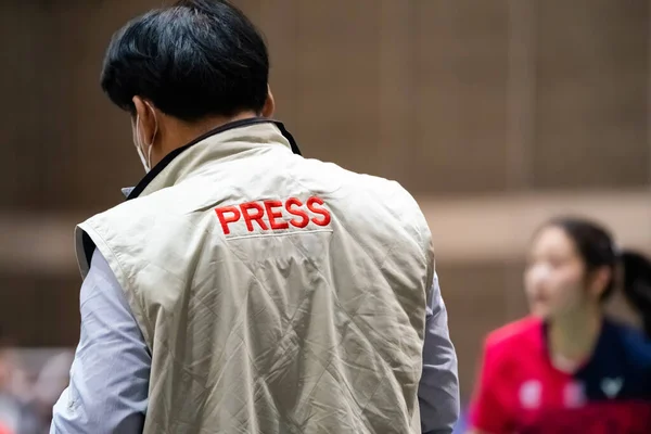 Backside of Asian Press man captures Sports news in Sports Stadium.