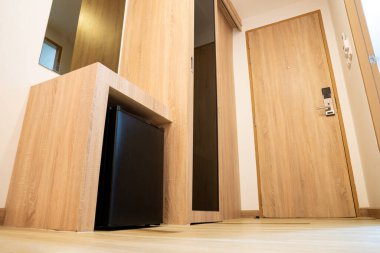 Otel odasındaki ahşap tezgahın altındaki küçük buzdolabı kapalıdır. Bu minimalist buzdolabı siyah renkli.. 