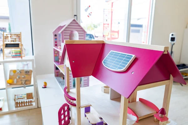 A solar cell is installed on the pink roof of a model wooden toy house.