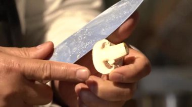 Volvariella volvacea 'yı kes ya da ahşap kesme tahtasına saman mantarı koy ve profesyonel bir şef tarafından mutfak bıçağıyla dilimle..
