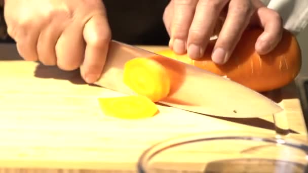 木製のまな板の上のスライスニンジンは プロのシェフによるキッチンナイフでスライス作品に — ストック動画