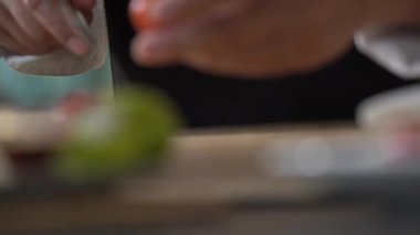 Profesyonel bir aşçının mutfak bıçağıyla tahta kesme tahtasıyla TOMATO 'yu dilimlemek..