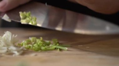 Ahşap bir tahtanın üzerinde sebze kişniş kökü kesip küçük parçalara ayırmak ve profesyonel bir şef tarafından mutfak bıçağıyla dilimlemek..