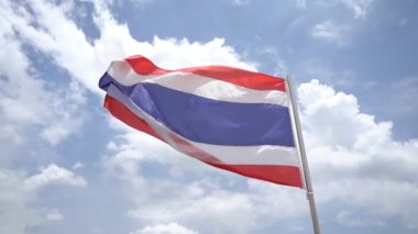 Tayland 'ın ulusal bayrağının yavaş hareketi mavi gökyüzünde rüzgar ve bulutlarla dalgalanıyor. Kırmızı, beyaz, mavi, beyaz ve kırmızı yatay çizgilerden oluşur..