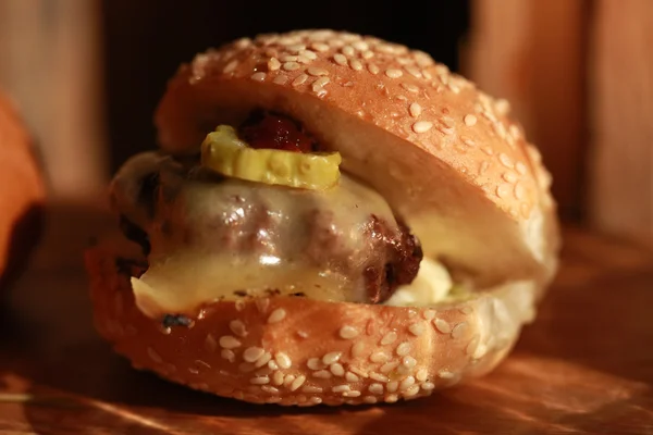 Hamburger schuifregelaar op een rustieke houten snijplank. — Stockfoto