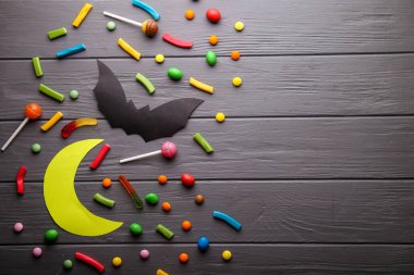 Kağıt cadılar bayramı süslemeleri ve tahta arka planda şekerler. Cadılar Bayramı konsepti. Düz yatış, üst görünüm