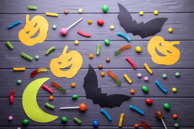 Kağıt cadılar bayramı süslemeleri ve tahta arka planda şekerler. Cadılar Bayramı konsepti. Düz yatış, üst görünüm